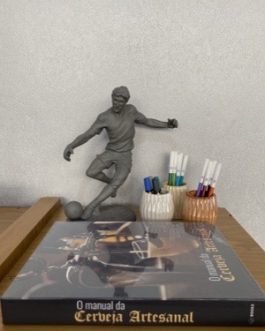 Escultura de Jogador de futebol chutando a bola sobre base, em resina